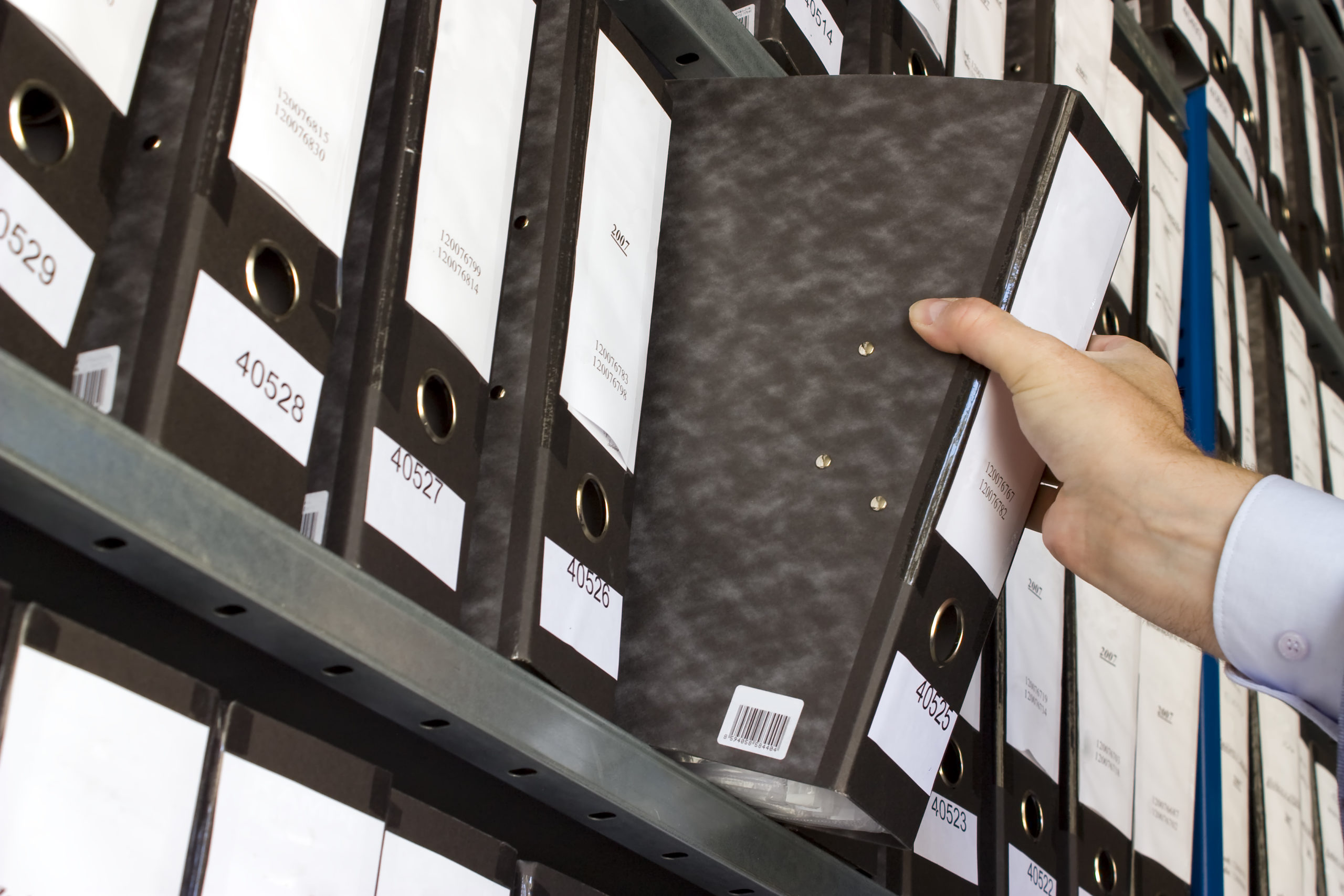 Man grabbing binder from shelf